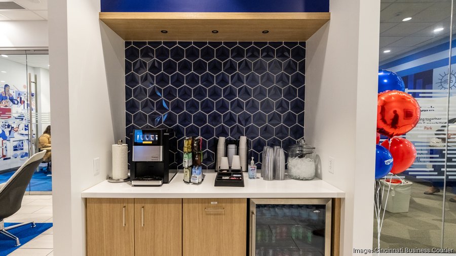 Modern US Bank coffee center featuring dark hexagonal tile backsplash, wood cabinetry, and beverage station with mini fridge